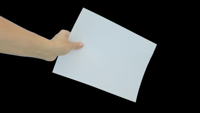 A hand holding a white empty piece of paper A4 with copy space against black background