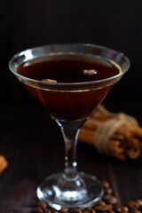 espresso martini cocktail. alcohol drinks on black background. glass of espresso with coffee beans and cinnamons sticks on dark wooden table. vertical