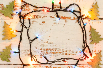 Frame made of Christmas lights and trees. Christmas lights on a wooden table. Christmas concept.