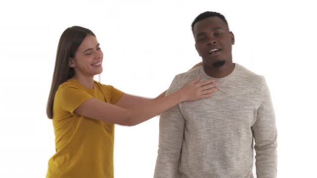 Young Caucasian woman being angry with her African boyfriend and trying to choke him. Quarrel in couple's relationship. Isolated on white background