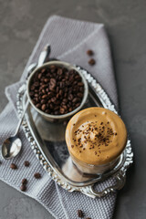 Glass of Iced Dalgona Coffee, trendy fluffy creamy whipped coffee and milk on grey background.