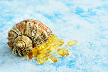 Golden fish oil capsules on a blue background - the concept of health and natural marine vitamins.