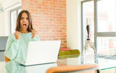 young pretty woman working ,shouting aggressively with an angry expression or with fists clenched...