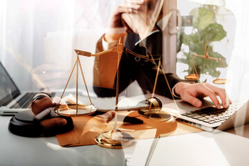 Justice and law concept.Male judge in a courtroom with the gavel, working with, computer and docking keyboard, eyeglasses, on table in morning light