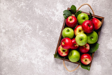 Ripe red and green apples in wooden box.