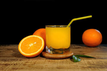 fresh orange juice and oranges on wooden table