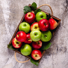 Ripe red and green apples in wooden box.