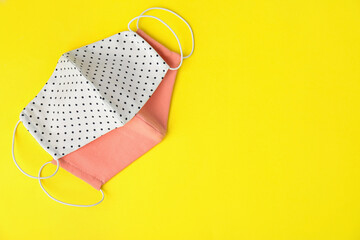 Homemade protective face masks on yellow background, flat lay. Space for text