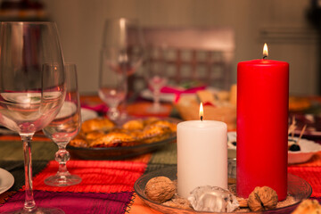 table with christmas dinner and two lighted candles at home