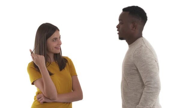 Young shy African man daring to speak to Caucasian woman. Lady flirting playing with curl. First meet or date. Romantic relationship concept.