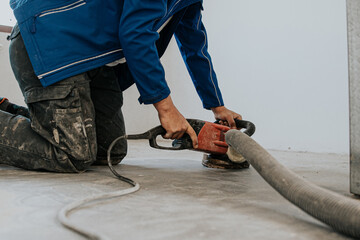 Construction worker using machine polishing surface floor smoothing and finishing hardener or epoxy...