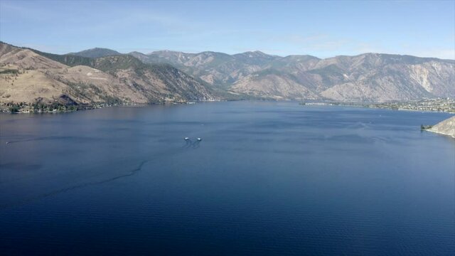 Drone flying over houses towards lake and mountains. 4k Lake Chelan aerial footage. Scenic mountains around lake. Beautiful lake drone footage.