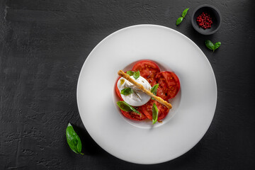 Burrata cheese and tomato salad with Basil and olive oil on a dark background