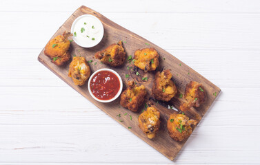 Chicken wings nuggets with sauces on wooden background .