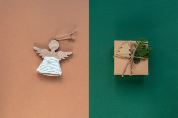 Christmas toy angel and gift in a box on beige and green background, Top view, flat lay