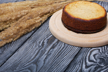 Freshly baked cupcake on a chalkboard. Nearby is a bouquet of dried grass. Against the background of black pine boards.