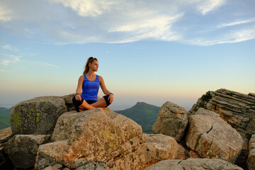 Fototapeta na wymiar young beautiful girl meditating girl on the mountain