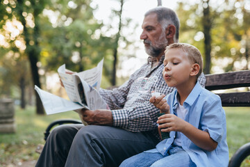 Fototapeta premium grandfather and grandson sitting on the bench in park