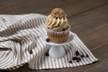 A Mini Chocolate Chip Cupcake with a Mini Chocolate Chip Cookie on Top on a Wooden Table
