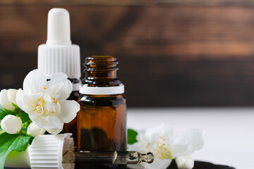 Fototapeta na wymiar natural cosmetic product, jasmine oil with glass bottles on a wooden table