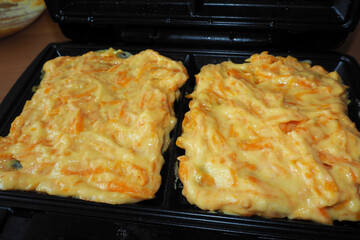 Belgian cornmeal egg and pumpkin waffle batter laid out in a waffle iron before cooking front view . gluten-free homemade food