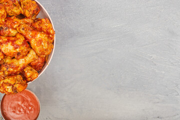 Buffalo chicken wings in a plate on a gray concrete background, copy space