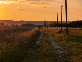 Sunset with the silhouette of high voltahe power posts. Beautiful natural landscape in the summer time