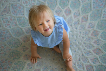 Fototapeta premium childhood, babyhood and people concept. happy little baby girl sitting on floor at home. view from above