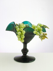 Bunch of green grapes on a beautiful green glass goblet