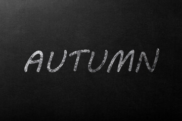 The inspiration "autumn" in white chalk on a dark blackboard.