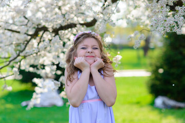 Fototapeta premium Pretty little girl in blooming apple tree garden on beautiful spring day
