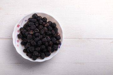 blackberries in a bowl on a white wooden background