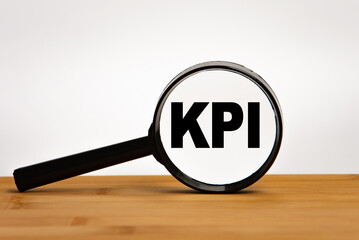 Focused on business concept. Magnifier glass with word KPI Key performance indicator on wooden...