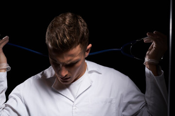 professional doctor in a medical gown with a stethoscope around his neck against a dark background cropped view
