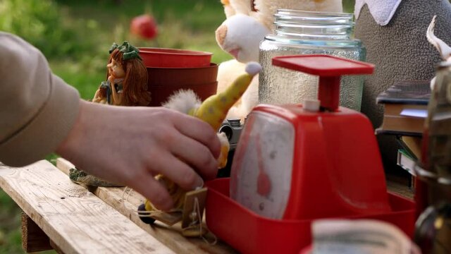 Close up  hand holding item at flea market. Garage sale in the yard. Searching for goods. 