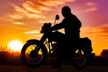 Naklejka na ściany i meble silhouette of a motorcyclist on a motorcycle, at sunset