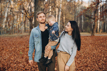 Fototapeta premium happy family mother father and baby on autumn walk in the park