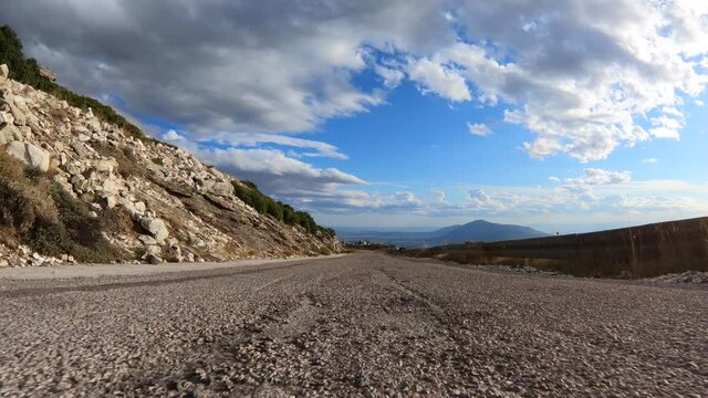 Fast tracking video from asphalt road perspective through a winding bumpy mountain road with with clear blue skies