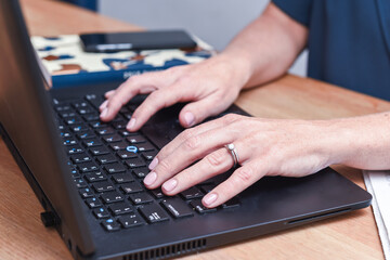 Woman working at home typing on a laptop computer keyboard