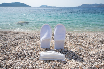 Summer vacation during coronavirus: medical mask and single use slippers from the hotel