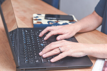 Woman working at home typing on a laptop computer keyboard