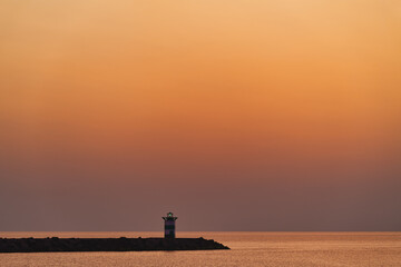 Golden hour sunset on the Scheveningen lighthouse with an even gradient orange color with space for...