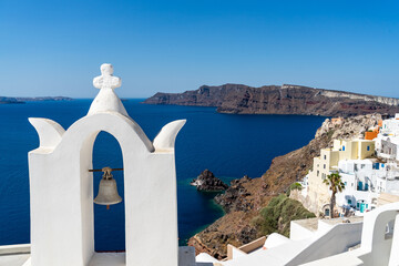 Fototapeta na wymiar Santorini caldera with Oia town and its famous orthodox church with white tower bell. Panoramic view