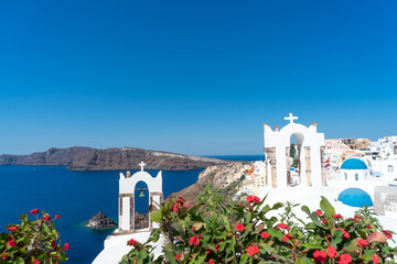 Fototapeta premium View of Santorini caldera with Oia town and famous old white tower bells and blue domes of orthodox churches