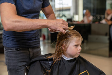 blond boy in a beauty studio getting a haircut and styling