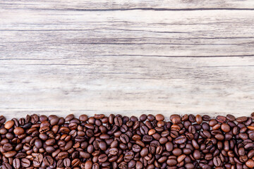 Coffee beans on wooden background. Pile of coffee. Coffee beans on a wooden background. Top view. Copy space.