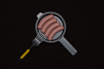 Toy sausages on a frying pan on a wooden background