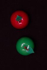 Red and green apple on a dark background. Plastic toy