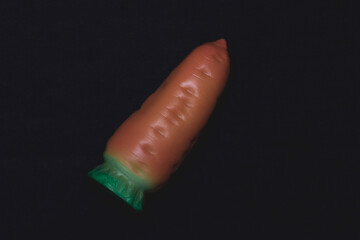 Toy carrot on a dark background.