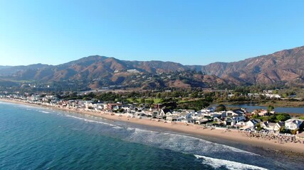 4K Aerial drone shot of Malibu Beach coastline in California with the blue Pacific Ocean with waves coming in and beach with nice houses on the background